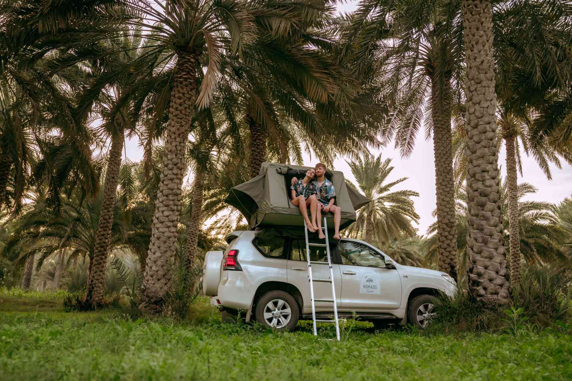 un couple qui campe au milieu des palmiers dans une tente de toit