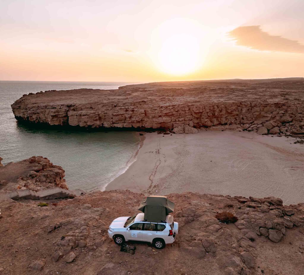 4x4 en haut d'une crique face à l'océan et la plage à Oman