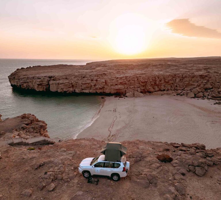 4x4 en haut d'une crique face à l'océan et la plage à Oman